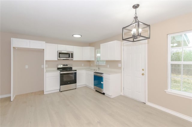 kitchen featuring pendant lighting, white cabinetry, appliances with stainless steel finishes, and light hardwood / wood-style flooring