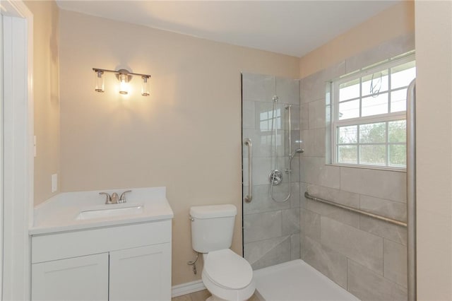 bathroom with toilet, vanity, and tiled shower