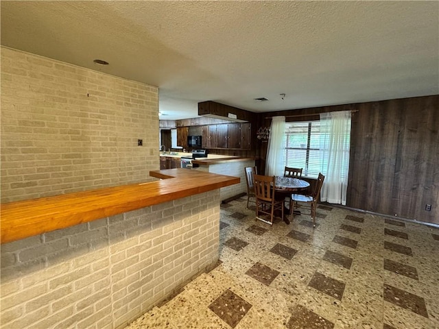 interior space with stainless steel range with electric cooktop, black microwave, a textured ceiling, and tile patterned floors