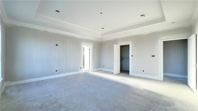 spare room featuring a tray ceiling, baseboards, concrete flooring, and ornamental molding