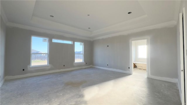 spare room with concrete floors, a raised ceiling, and baseboards