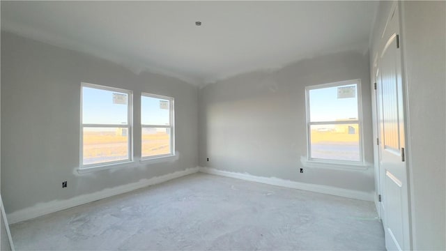 spare room featuring baseboards and concrete flooring