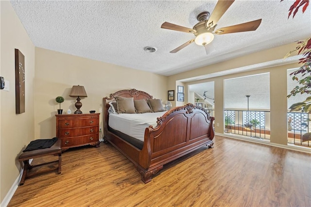 bedroom featuring a textured ceiling, light wood-type flooring, visible vents, and baseboards