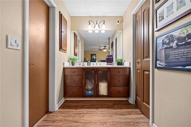 bathroom with a ceiling fan, vanity, a textured ceiling, and wood finished floors