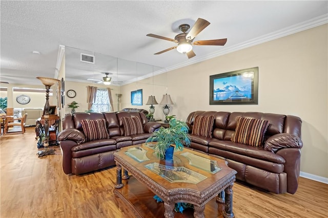 living room with ornamental molding, light wood finished floors, visible vents, and a ceiling fan