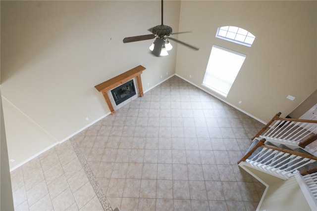 unfurnished living room with ceiling fan and high vaulted ceiling