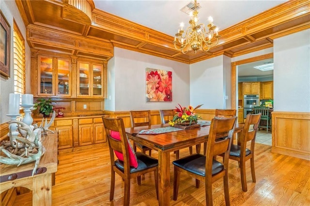 dining room with crown molding, coffered ceiling, a notable chandelier, and light wood-type flooring