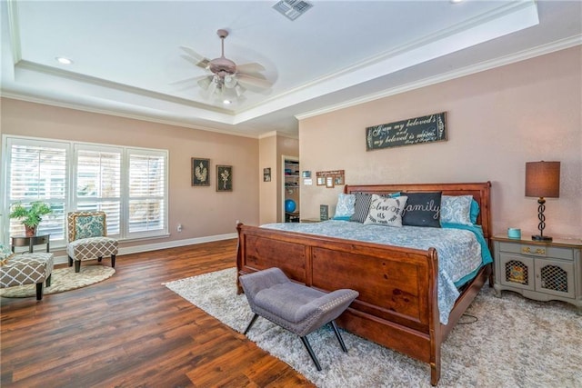 bedroom with crown molding, hardwood / wood-style flooring, and a raised ceiling