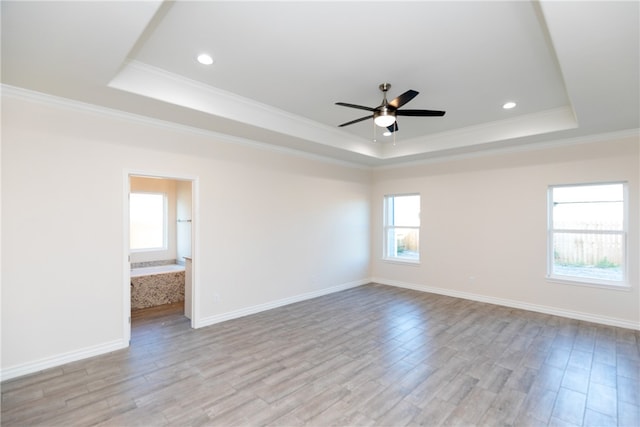 unfurnished room featuring light hardwood / wood-style flooring, a raised ceiling, ceiling fan, and ornamental molding