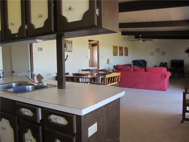 kitchen with carpet, sink, dark brown cabinets, ceiling fan, and beam ceiling