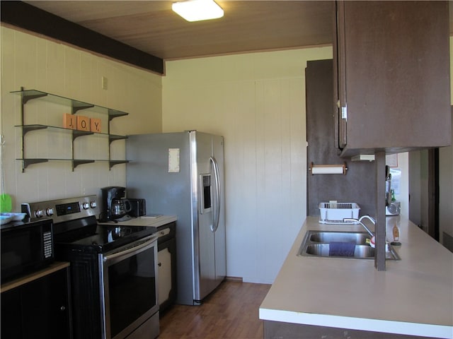 kitchen featuring dark hardwood / wood-style floors, beam ceiling, sink, dark brown cabinetry, and stainless steel appliances