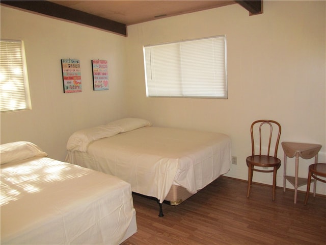 bedroom featuring dark hardwood / wood-style flooring and beamed ceiling