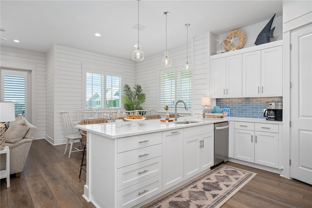 kitchen with backsplash, dishwasher, sink, hanging light fixtures, and white cabinets