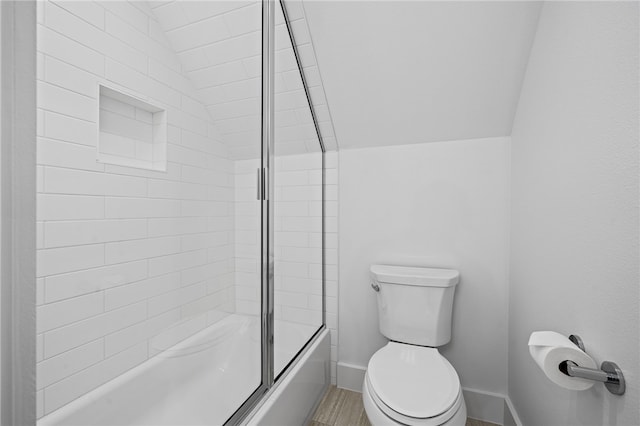 bathroom featuring toilet, shower / bath combination with glass door, and vaulted ceiling