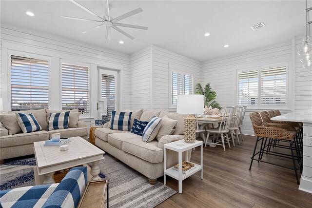 living room with ceiling fan, a wealth of natural light, dark hardwood / wood-style floors, and wood walls