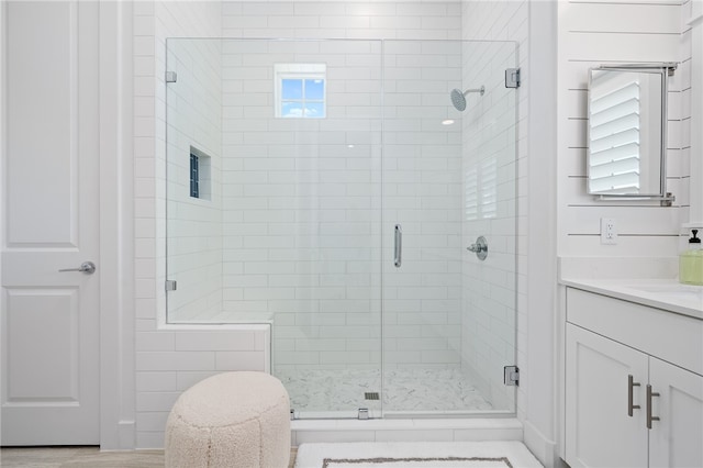 bathroom featuring a healthy amount of sunlight, walk in shower, and vanity