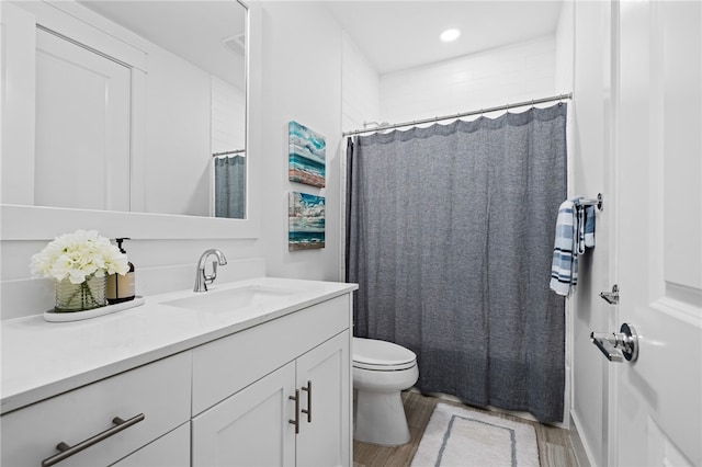 bathroom with toilet, vanity, curtained shower, and hardwood / wood-style floors