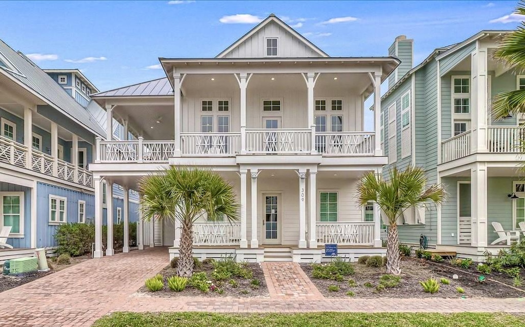 view of front of property featuring metal roof, a standing seam roof, decorative driveway, a porch, and board and batten siding