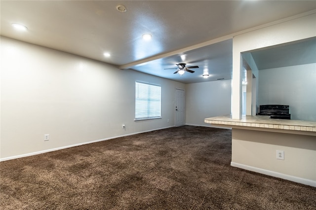 unfurnished living room with ceiling fan and dark carpet