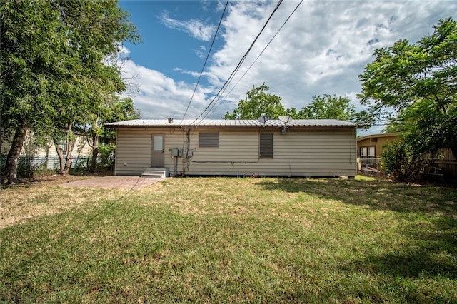 back of house with a lawn and a patio