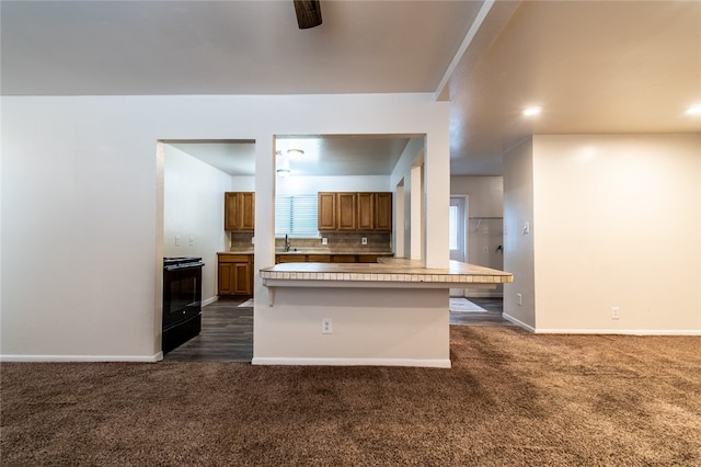 kitchen with backsplash, a breakfast bar area, black range, and dark colored carpet