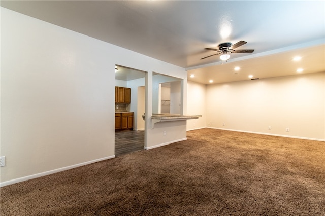 unfurnished living room with ceiling fan and dark carpet