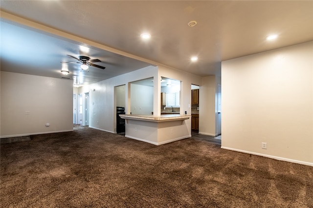 unfurnished living room with dark colored carpet and ceiling fan