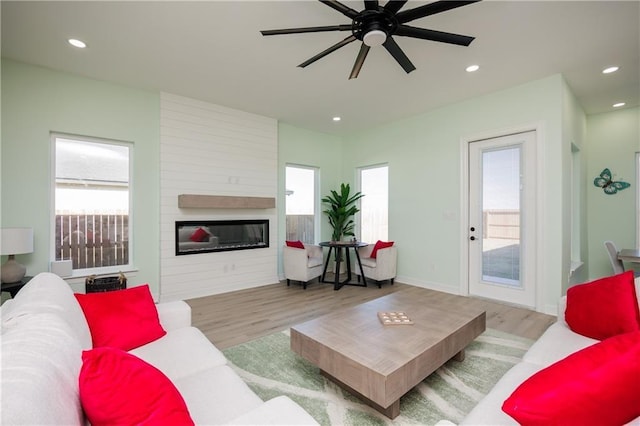 living area featuring a fireplace, wood finished floors, a ceiling fan, and recessed lighting