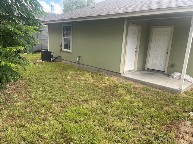 back of house with central AC unit and a yard