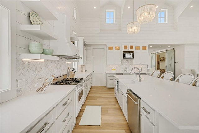 kitchen featuring decorative light fixtures, white cabinets, stainless steel appliances, a barn door, and an inviting chandelier