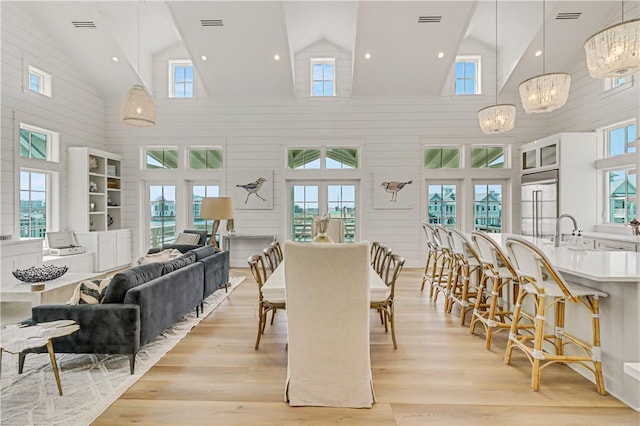 dining space featuring lofted ceiling, a chandelier, sink, and light hardwood / wood-style flooring