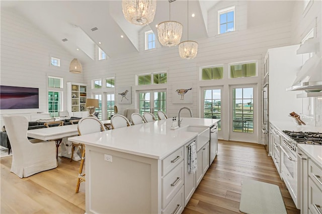 kitchen featuring a breakfast bar, white cabinetry, decorative light fixtures, a chandelier, and a kitchen island with sink