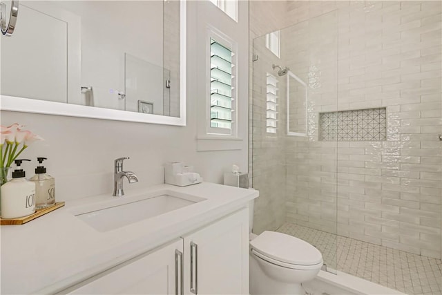 bathroom featuring vanity, a tile shower, and toilet