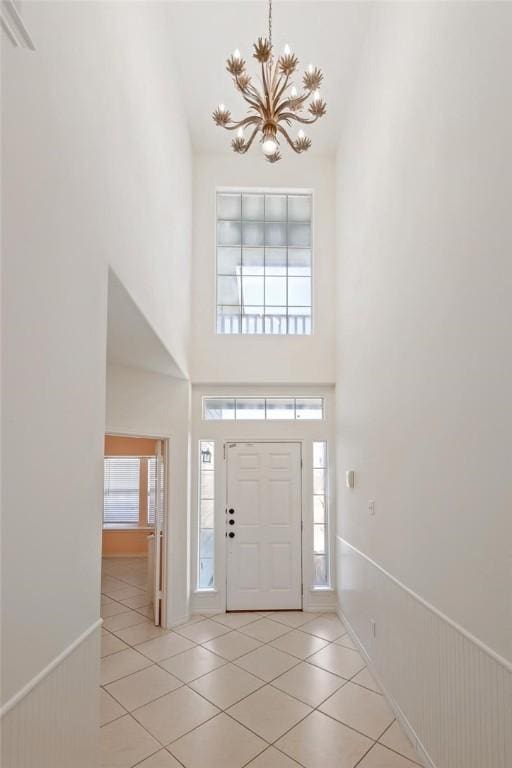 13534 Bullion Ct, Corpus Christi, TX 78418 - entrance foyer with a chandelier, a towering ceiling, light tile patterned flooring, and a wainscoted wall