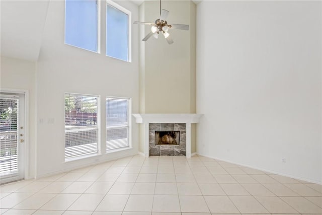 13534 Bullion Ct, Corpus Christi, TX 78418 - unfurnished living room with a ceiling fan, a tile fireplace, a towering ceiling, light tile patterned floors, and baseboards