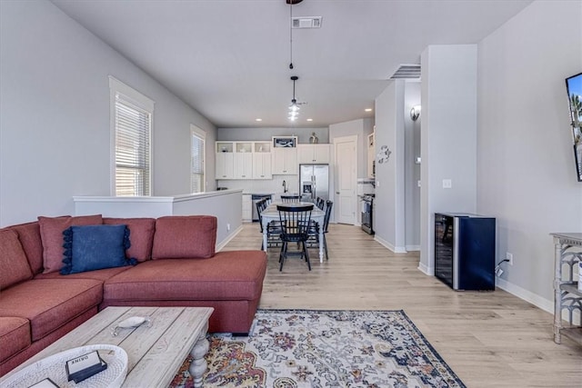 living room with beverage cooler and light hardwood / wood-style floors