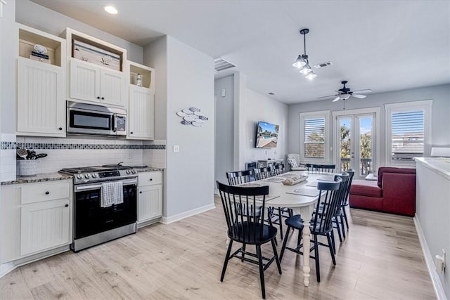 kitchen with white cabinetry, appliances with stainless steel finishes, hanging light fixtures, and light stone counters