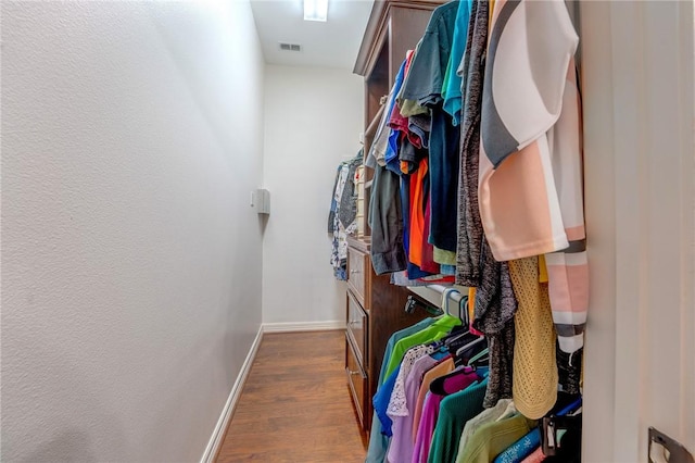 walk in closet with dark hardwood / wood-style floors