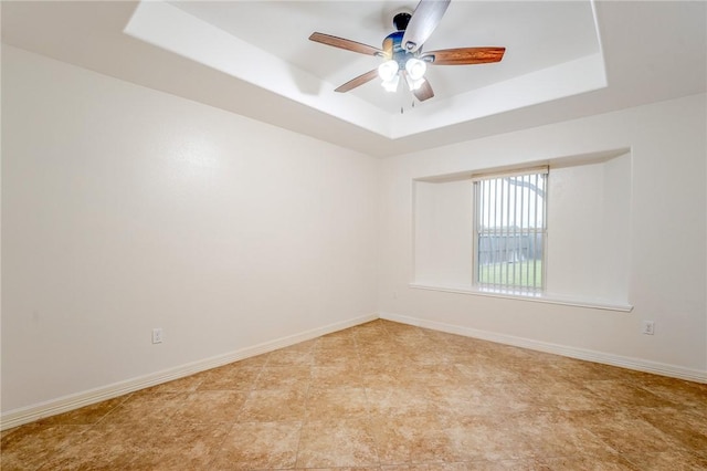 unfurnished room featuring a raised ceiling and ceiling fan