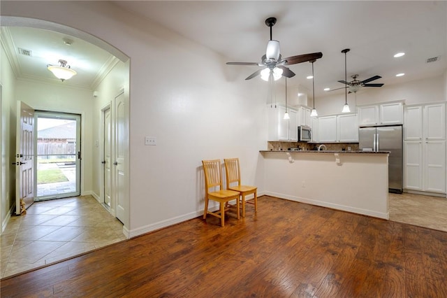 kitchen featuring kitchen peninsula, appliances with stainless steel finishes, ceiling fan, white cabinets, and dark hardwood / wood-style floors