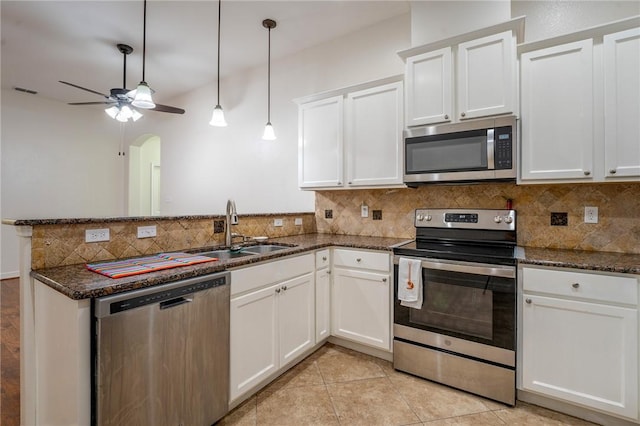 kitchen featuring dark stone counters, white cabinetry, sink, and stainless steel appliances