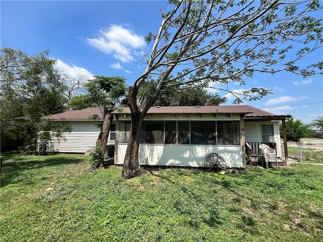 rear view of house featuring a sunroom and a yard