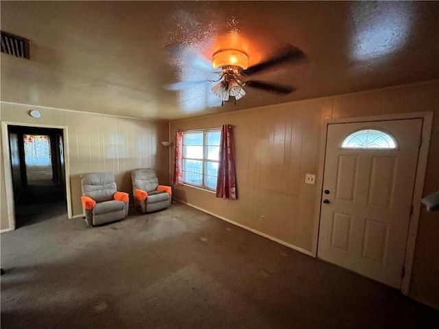 entryway with carpet, ceiling fan, and wooden walls