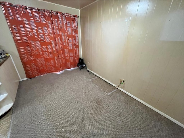 carpeted spare room featuring wood walls