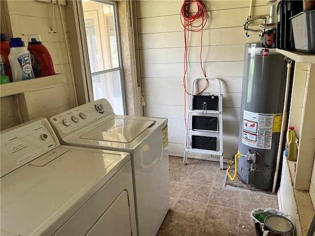 laundry room with water heater, light tile patterned flooring, wooden walls, and washing machine and clothes dryer