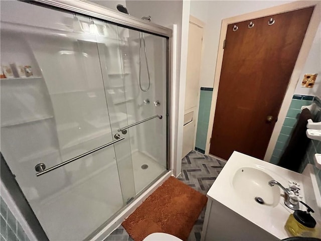 bathroom featuring vanity, a shower with door, and parquet flooring