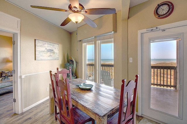 dining area featuring ceiling fan, a water view, lofted ceiling, and light hardwood / wood-style floors