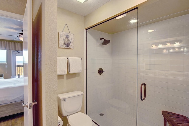 bathroom featuring a shower with door, ceiling fan, a textured ceiling, hardwood / wood-style floors, and toilet