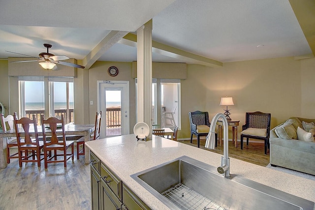 kitchen with light hardwood / wood-style floors, a water view, sink, ceiling fan, and beam ceiling