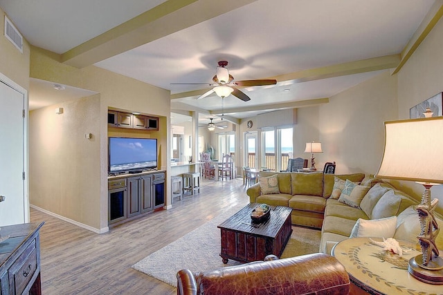 living room featuring light hardwood / wood-style flooring, beamed ceiling, and ceiling fan